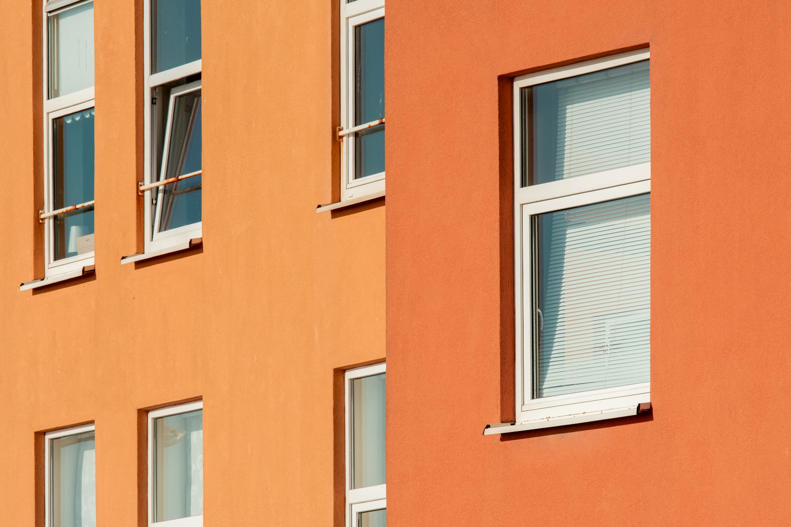Close-up view of orange building exterior with multiple windows in urban setting.